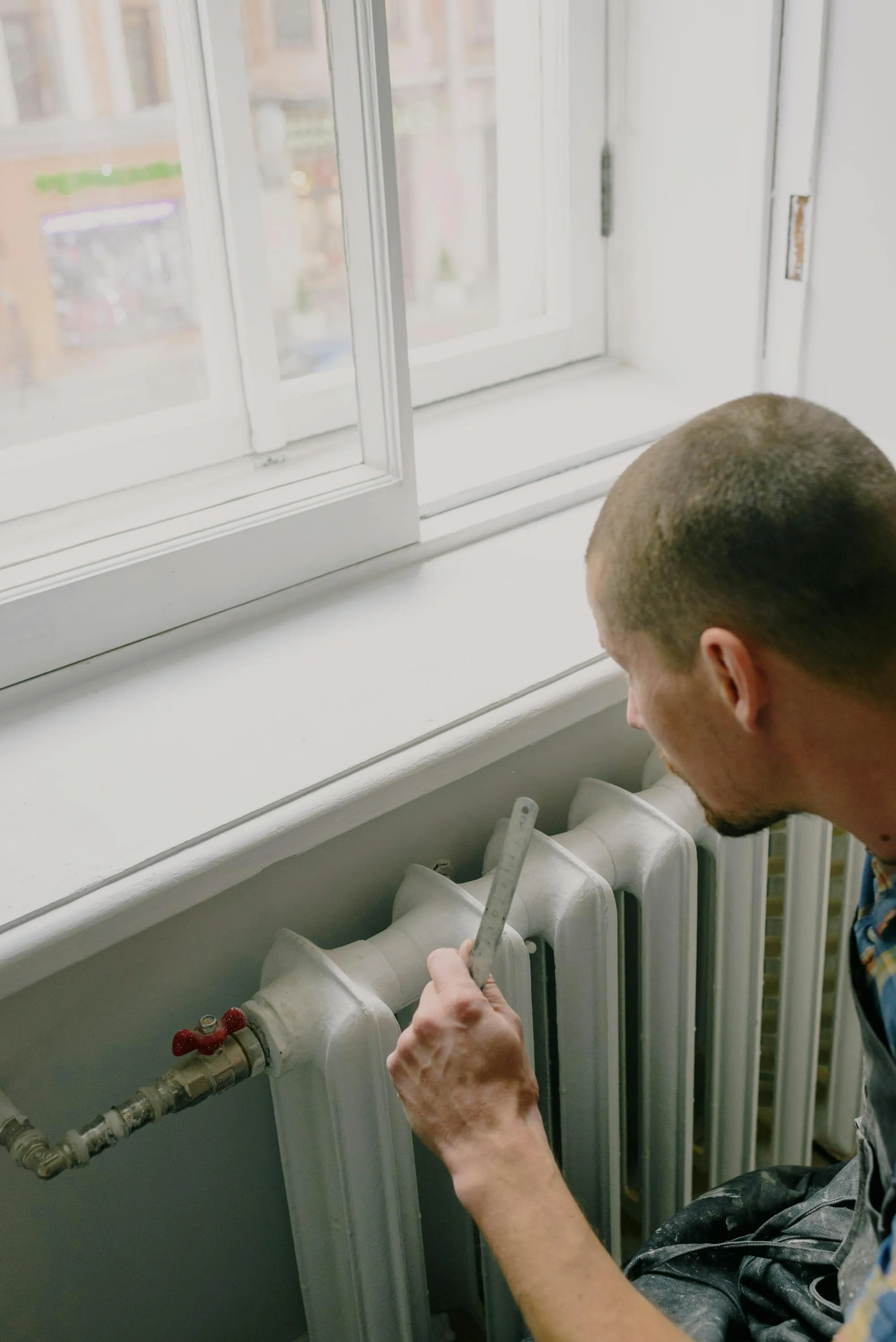 Engineer measuring a cast-iron radiator in a London period property