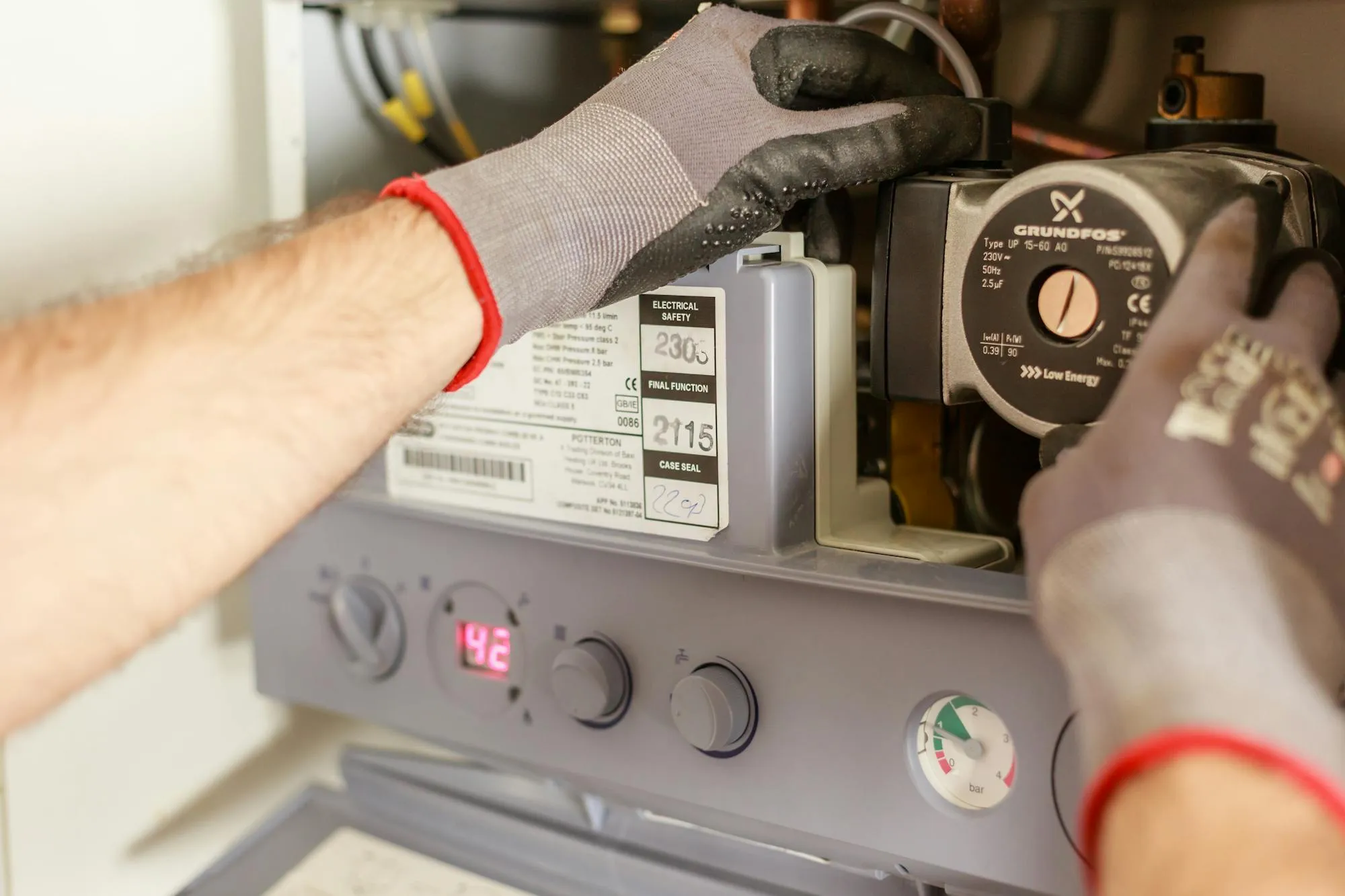 Engineer servicing a UK domestic boiler with pressure gauge visible